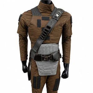 May include: A brown long-sleeved tactical suit featuring a high collar, black rectangular patches on the shoulders and legs, a black diagonal shoulder strap with loops, and a gray padded abdominal guard secured by a black utility belt with pouches.