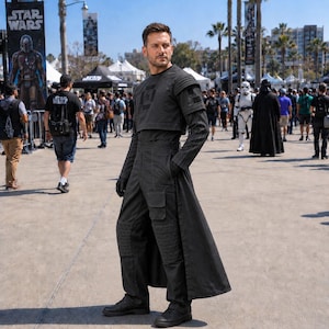 May include: A dark gray tactical outfit consisting of a short-sleeved top with ribbed shoulder detailing, long sleeves, and high-waisted trousers featuring a long, open-front skirt overlay, cargo pockets, and ribbed knee panels, paired with black boots.