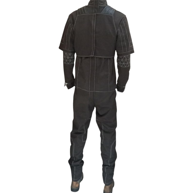 K&ouml;nnte beinhalten: Ein schwarzer Overall mit Stehkragen, kurzen &Auml;rmeln und langer Hose. Das Kleidungsst&uuml;ck ist mit wei&szlig;en Kontrastn&auml;hten versehen, darunter geometrische Dreiecksmuster an den &Auml;rmeln sowie vertikale Linien entlang der Hosenbeine.