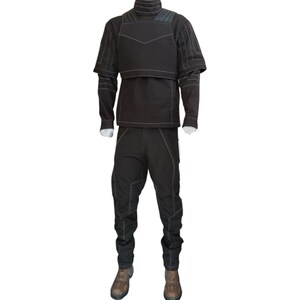 K&ouml;nnte beinhalten: Ein schwarzes Set aus lang&auml;rmeligem Oberteil und passender Hose mit hohem Kragen und strukturiertem Brustaufsatz. Das Kleidungsst&uuml;ck ist mit markanten wei&szlig;en Ziern&auml;hten an &Auml;rmeln, Rumpf und Beinen versehen und wird mit braunen Stiefeln kombiniert.