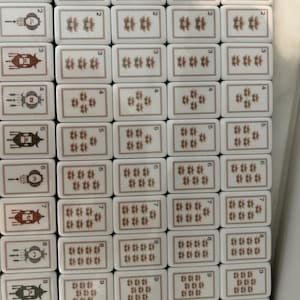 May include: A collection of rectangular mahjong tiles arranged in a grid. The left column features tiles with lantern illustrations and numbers one through nine, plus a cat tile. The remaining columns display tiles with floral patterns and numbers.