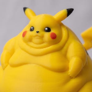 May include: A yellow Pikachu figurine with a rounded, stout body, black-tipped ears, red circular cheeks, and a lightning bolt-shaped tail. The character has small black eyes, a tiny nose, and a wide, soft-looking form with visible layer lines.
