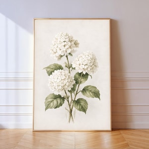 May include: A framed vertical wall art print featuring a botanical illustration of three white hydrangea flower clusters with green leaves on a light cream background. The artwork is enclosed in a thin, light-colored wooden frame.