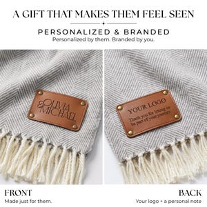 May include: A grey and white herringbone patterned throw blanket featuring a rectangular tan leather patch attached with four brass rivets. The front patch displays the text OLIVIA MICHAEL, while the back patch displays YOUR LOGO and Thank you for letting us be part of your journey. The blanket has cream-coloured fringe at the bottom edge.