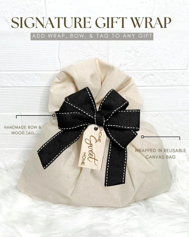 a beige gift bag with a black bow and a tag that says "Home Sweet Home". The bag is described as a "Signature Gift Wrap" and is made of a reusable canvas bag.