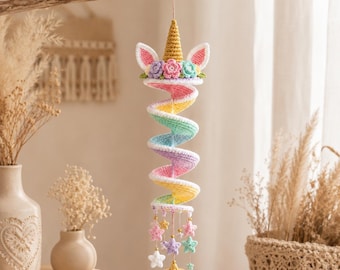 May include: A crochet unicorn spiral hanging decoration featuring a gold horn, white ears with pink centers, and pastel flowers. The body is a multi-colored spiral in yellow, green, blue, and pink, finished with dangling crochet stars and gold beads.