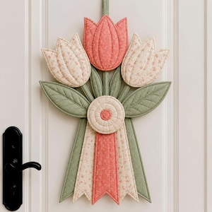 May include: A quilted fabric wall hanging shaped like a bouquet of three tulips. The central tulip is solid coral, while the two side tulips feature a cream fabric with a small floral print. Green quilted leaves and stems extend downward.