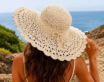 May include: A wide-brimmed beige crochet sun hat featuring an intricate openwork pattern along the brim, a rounded crown, and a decorative cord tied into a bow at the base of the crown, finished with small wooden beads at the ends of the cord.