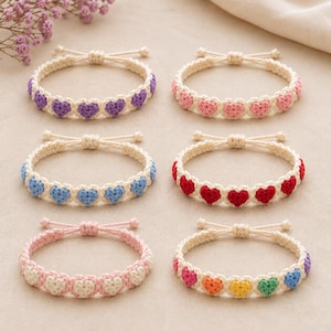 Può includere: Sei braccialetti all'uncinetto fatti a mano con una serie di piccoli cuori in vari colori, tra cui viola, rosa, blu, rosso e una versione multicolore. Ogni braccialetto è realizzato con cordino bianco sporco e ha un nodo scorsoio regolabile.