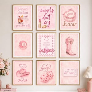 May include: A gallery wall set of nine pink-themed art prints in gold frames. The prints feature illustrations of a cocktail, lipstick, a cowboy hat, an eight ball, a boot with flowers, dice, and text including 'cowgirls don't cry' and 'yee haw'.