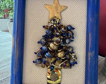 Christmas tree collage in a blue frame with gold metallic accents. Created with a mixture of beads from necklaces, bracelets and earrings.