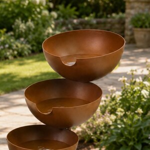 1. Rustic metal rain catcher bird bath stake with three cascading bowls displayed in a cottage garden flower bed.
