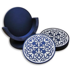May include: A set of circular drink coasters featuring a dark blue and white intricate geometric pattern. The coasters are stacked and stored in a matching dark blue circular holder with a curved side opening for easy access to the items.