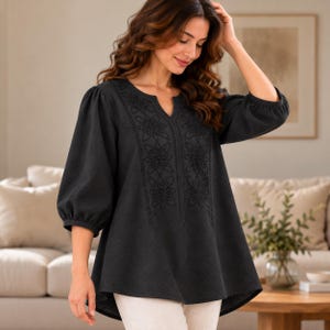 May include: A black tunic top featuring three-quarter length sleeves and a notched neckline. The front panel is decorated with tonal floral embroidery in a symmetrical pattern. The garment has a relaxed fit and a slightly longer back hemline.