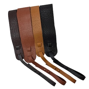 May include: Four textured straps in dark brown, reddish-brown, tan, and black. Each strap features a wide main section with a pebbled surface, a sliding loop, and a thinner adjustable extension piece secured with small metal rivets at the bottom end.