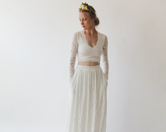 May include: A white lace crop top and matching maxi skirt with a V-neckline and long sleeves. The skirt has pockets.