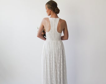 May include: White lace wedding dress with a low back and a halter neckline. The dress has a flowing skirt and is perfect for a beach wedding.