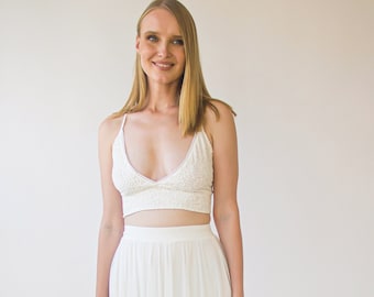 May include: A white lace crop top and a white maxi skirt with lace trim. The skirt has multiple layers and a flowy silhouette.