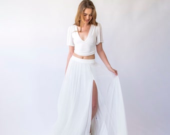 May include: A white crop top with a V-neck and short sleeves paired with a white maxi skirt with a thigh-high slit.