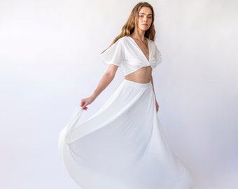 May include: A white two-piece outfit with a knotted crop top and a flowing maxi skirt.