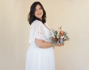 May include: A woman in a white lace wedding dress with a long skirt and a lace overlay. She is holding a bouquet of dried flowers in her right hand.