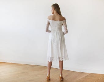 May include: A white off-the-shoulder lace dress with long sleeves and a midi-length skirt. The dress has a fitted bodice and a flowing skirt.