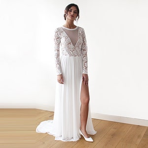 Puede incluir: Un vestido blanco maxi de manga larga, con un corpi&ntilde;o de encaje transparente y una abertura en la pierna hasta el muslo. El vestido tiene un escote redondo y un corpi&ntilde;o ajustado.