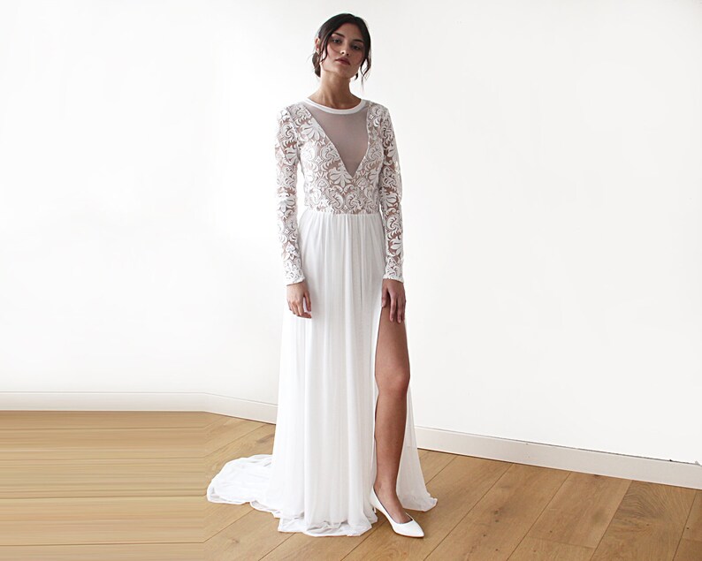 Puede incluir: Un vestido blanco maxi de manga larga, con un corpi&ntilde;o de encaje transparente y una abertura en la pierna hasta el muslo. El vestido tiene un escote redondo y un corpi&ntilde;o ajustado.