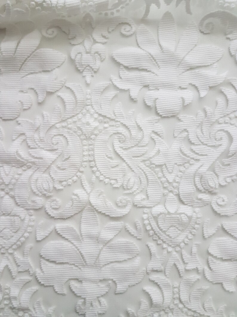 Puede incluir: Tela blanca con un patr&oacute;n floral en relieve. La tela tiene una textura delicada y de encaje.