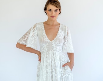 May include: A white lace dress with a V-neckline and 3/4 sleeves. The dress has a flowing skirt and a fitted bodice.