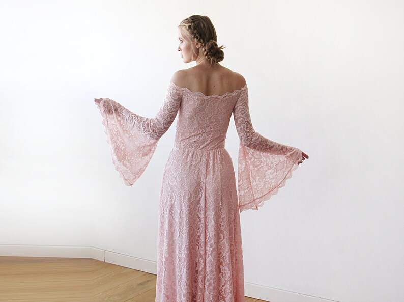 May include: A long, off-the-shoulder, pink lace dress with bell sleeves. The dress has a fitted bodice and a flowing skirt.