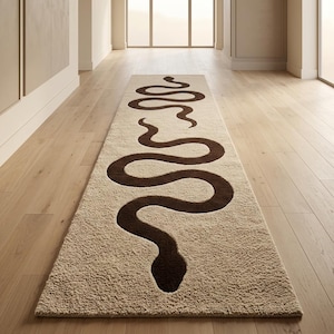 Puede incluir: Una alfombra de pasillo larga y rectangular con una superficie texturizada de color crema y un gran patrón de serpiente sinuosa de color marrón oscuro que se extiende a lo largo de toda la alfombra, desde la cabeza hasta la cola.