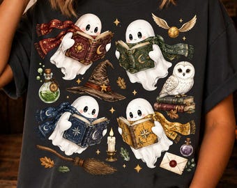 May include: A dark gray t-shirt featuring a graphic print of four white ghosts reading books, each wearing a different colored scarf. The design includes a witch hat, a white owl, a broomstick, a golden snitch, potion bottles, and a wax-sealed envelope.