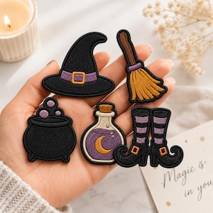 May include: A set of five embroidered patches featuring a black witch hat with a purple band, a brown broomstick, a black cauldron with purple bubbles, a glass bottle containing purple liquid with a yellow crescent moon, and black striped boots.