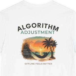May include: A white t-shirt featuring a graphic of a person in a hammock between two palm trees at sunset. The text reads ALGORITHM ADJUSTMENT, RESET RESTORE RECONNECT, and OFFLINE FEELS BETTER. The design includes a warm orange and blue color palette.