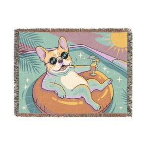 Könnte beinhalten: Eine gewebte Wohndecke mit einer französischen Bulldogge, die eine schwarze Sonnenbrille trägt und einen Cocktail hält, während sie auf einem orangefarbenen Schwimmring in einem Pool treibt. Das Motiv zeigt eine gelbe Sonne, Palmenblätter und Sterne.