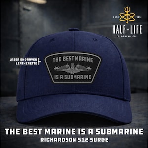 May include: Navy blue baseball cap with a patch that reads "THE BEST MARINE IS A SUBMARINE." The patch features a submarine graphic. The cap also has the text "RICHARDSON 512 SURGE" and "HALF-LIFE CLOTHING CO."