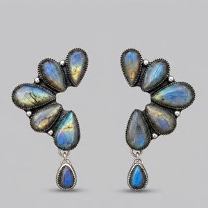 Peut inclure: Une paire de boucles d'oreilles en argent avec plusieurs pierres de labradorite en forme de goutte. Chaque boucle est disposée en un groupe incurvé en éventail avec une goutte pendante à la base, révélant des reflets bleus et dorés.