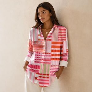 Op de afbeelding: Een overhemd met lange mouwen en knoopsluiting, voorzien van een levendig patchworkpatroon van verticale en horizontale strepen in tinten roze, rood, oranje en wit. Het overhemd heeft een klassieke kraag en mouwen met manchetten.