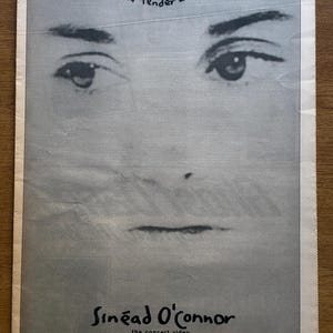 Peut inclure: Une publicité de magazine vintage en noir et blanc présentant un gros plan sur des yeux et le texte 'Soft and tender and Sweet' en haut. En dessous, le texte indique 'Sinéad O'Connor', 'the concert video', 'THE VALUE OF IGNORANCE' et 'songs from 'the lion & the cobra' on l.p., c.d. & cass.'