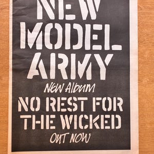 Può includere: Un annuncio musicale vintage in bianco e nero stampato su carta. Il testo recita New Model Army, New Album, No Rest For The Wicked, Out Now e 25th May, 1985 New Musical Express—Page 13. Il design presenta caratteri audaci in stile stencil.