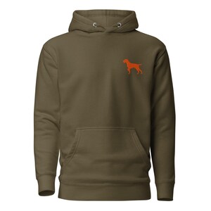 Peut inclure: Un sweat-shirt à capuche vert olive arborant une petite silhouette de chien orange brodée sur la poitrine gauche. Le vêtement est doté d'une poche kangourou à l'avant, de manches longues à poignets côtelés et d'un cordon de serrage assorti.