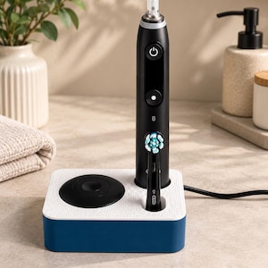 May include: A black electric toothbrush with a digital display and a power button, standing upright in a white and navy blue charging base. The toothbrush features a round brush head with blue and white bristles and the Oral-B iO logo on the handle.