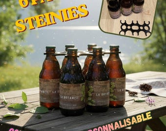 May include: A six-pack of brown glass bottles labeled La Botanist held together by a black plastic carrier. The text 6 PACK STEINIES, COULEUR AU CHOIX, and PERSONNALISABLE appears on the image. The bottles are arranged in a grid on a wooden surface.