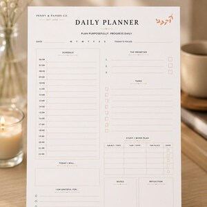 Puede incluir: Una hoja de planificador diario blanca con texto negro y detalles en marrón claro. Incluye secciones para un horario de 06:00 a 22:00, prioridades, tareas, un plan de estudio o trabajo, notas y reflexión. El encabezado dice Penny & Papers Co. Daily Planner.