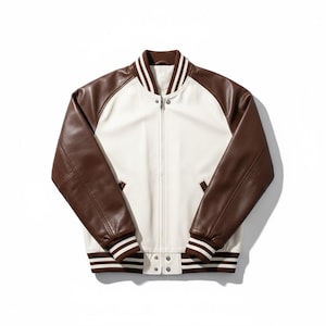 Puede incluir: Una chaqueta tipo varsity con cuerpo color crema y mangas marrón oscuro. La chaqueta tiene cuello, puños y dobladillo acanalados con rayas blancas. Incluye una cremallera frontal completa, dos bolsillos laterales y dos botones a presión.