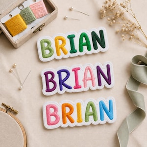 Op de afbeelding: Drie geborduurde patches met de naam BRIAN in verschillende kleuren. De bovenste patch heeft groene, gele en donkergroene letters. De middelste patch heeft paarse, blauwe, roze en donkerpaarse letters. De onderste patch heeft roze, oranje, gele, groene en blauwe letters.