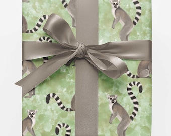 May include: A rectangular gift box wrapped in light green paper featuring a repeating pattern of grey and white lemurs with long striped tails. The package is tied with a smooth, solid grey satin ribbon that is knotted into a decorative bow.