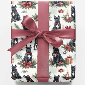 May include: A square gift box wrapped in white paper featuring a repeating pattern of black dogs, red bows, green pine branches, and brown gift boxes. A wide, dark red satin ribbon is tied in a large bow around the center of the package.