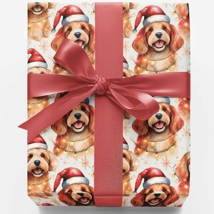 May include: A rectangular gift box wrapped in white paper featuring a repeating pattern of golden-brown dogs wearing red Santa hats and wrapped in string lights, tied with a wide, smooth, dark red satin ribbon and a centered bow.
